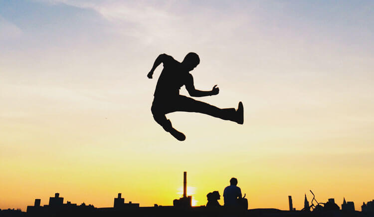 Silhouette of kid jumping against sunset