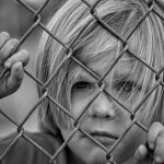 boy_looking_fence_chain_link_young_child_male_portrait-772750